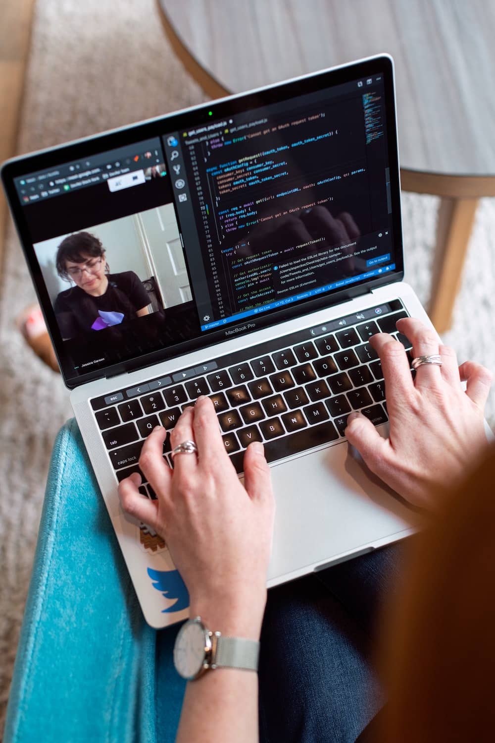 closeup of a student’s laptop, showing a video call on one side of the screen and a code editor on the other other side
